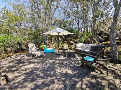 a patio with a couch and an umbrella and chairs at Villa San Antonu, Santa Giulia in Porto-Vecchio