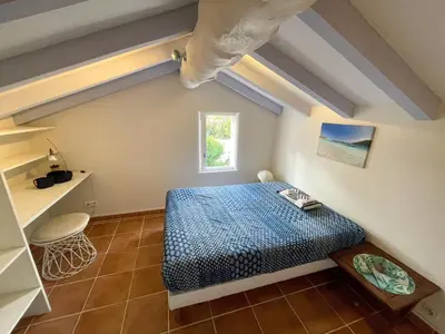 a bedroom with a blue bed in a attic at Villa San Antonu, Santa Giulia in Porto-Vecchio