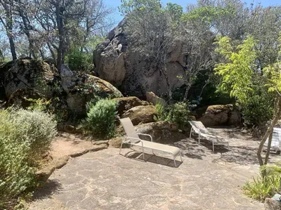 two white chairs sitting in the middle of a garden at Villa San Antonu, Santa Giulia in Porto-Vecchio