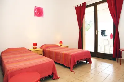 two beds in a room with a large window at Villa Tizzano, Santa Giulia in Porto-Vecchio