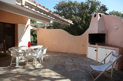 a patio with a table and chairs and a pizza oven at Villa Tizzano, Santa Giulia in Porto-Vecchio