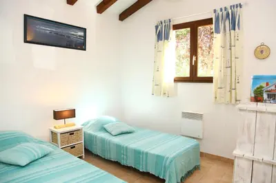 a bedroom with two beds and a tv and a window at Villa Tizzano, Santa Giulia in Porto-Vecchio