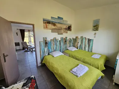 two beds in a room with green sheets at Villa Arca, 5min du centre de Porto-Vecchio in Porto-Vecchio