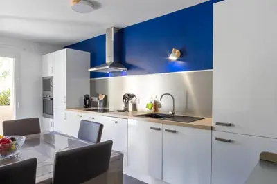 a kitchen with white cabinets and a blue wall at Le Petra - Appt climatisé proche de la plage in Ajaccio
