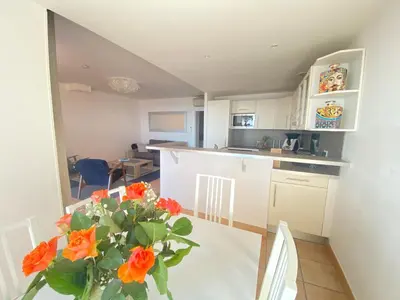 a kitchen with a table and a vase with orange flowers at Mini villa Hameaux des Sanguinaires AJACCIO in Ajaccio