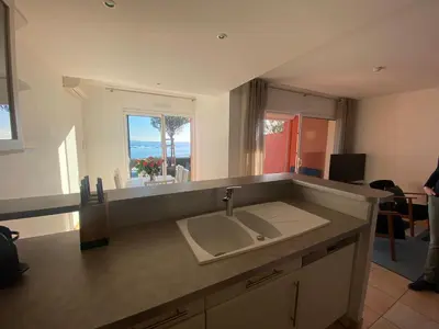 a kitchen with a sink and a view of the ocean at Mini villa Hameaux des Sanguinaires AJACCIO in Ajaccio
