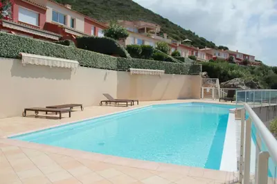 a swimming pool with two benches next to a building at Mini villa Hameaux des Sanguinaires AJACCIO in Ajaccio