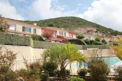 a view of a building with a mountain in the background at Mini villa Hameaux des Sanguinaires AJACCIO in Ajaccio