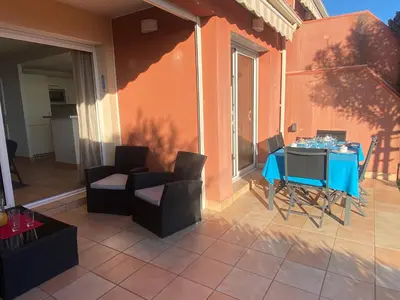 a patio with a blue table and chairs on a balcony at Mini villa Hameaux des Sanguinaires AJACCIO in Ajaccio