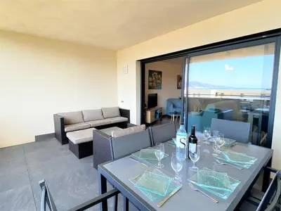 a living room with a blue couch and a kitchen at Appartement Le Frassu PORTICCIO in Porticcio