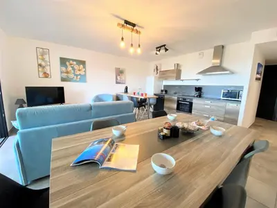 a living room with a blue couch and a kitchen at Appartement Le Frassu PORTICCIO in Porticcio