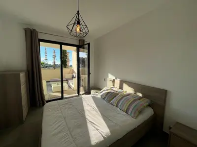 a bedroom with a bed with a view of a patio at Appartement Le Frasso PORTICCIO in Porticcio