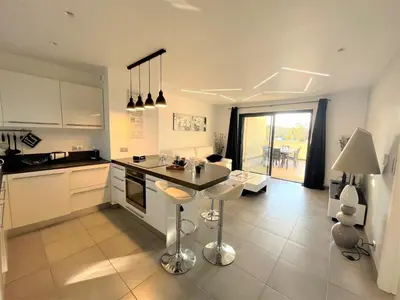 a kitchen with white cabinets and a table and chairs at Appartement Le Frasso PORTICCIO in Porticcio