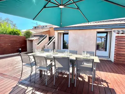 a table with chairs and an umbrella on a deck at Villa L'Ondella PORTICCIO in Porticcio