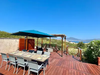 a table with chairs and an umbrella on a deck at Villa L'Ondella PORTICCIO in Porticcio