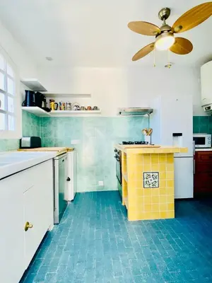 a kitchen with a yellow and blue floor and a ceiling fan at Villa Montalbo vue mer avec grande terrasse & plage à proximité - idéale famille et groupe de 2 à 10 personnes in Cargèse