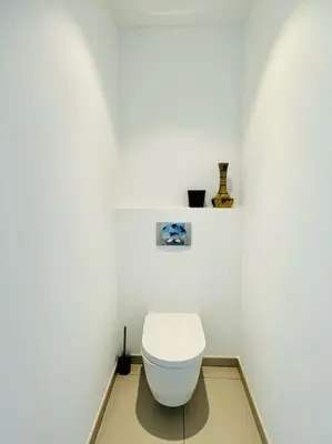 a bathroom with a white toilet in a white wall at 