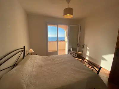 a bedroom with a bed with a view of the ocean at VILLA 5 pièces 8 couchages PORTICCIO in Porticcio