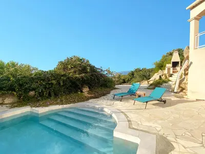 a swimming pool with two blue chairs next to a house at VILLA 5 pièces 8 couchages PORTICCIO in Porticcio