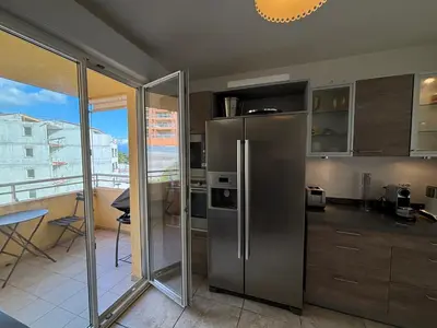a kitchen with a stainless steel refrigerator and a balcony at Appartement Le Diana Sanguinaires Ajaccio in Ajaccio