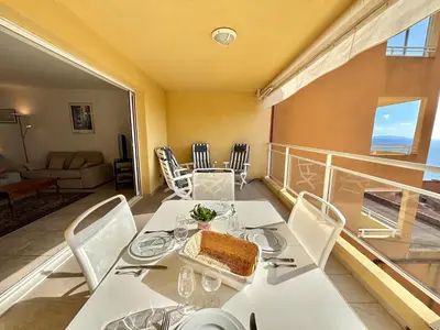a dining room with a table with a cake on a balcony at Appartement Le Diana Sanguinaires Ajaccio in Ajaccio