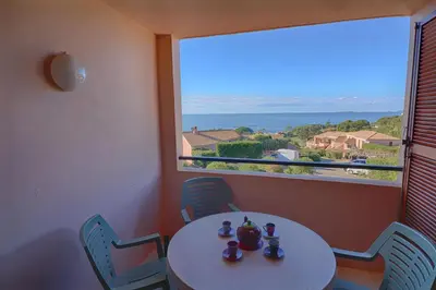 a table and chairs in a room with a large window at Appartement Les Couchants PORTICCIO in Porticcio