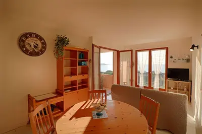 a dining room with a table and chairs and a clock at Appartement Les Couchants PORTICCIO in Porticcio