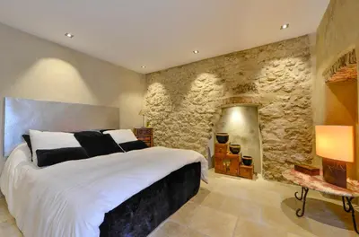 a bedroom with a large bed and a stone wall at casa teppe rosse in Aléria