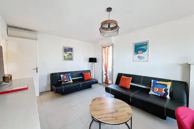 a living room with two black couches and a table at Pretty cocoon with harbour view in Porto-Vecchio