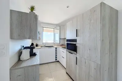 a kitchen with white cabinets and a large wooden wall at Pretty cocoon with harbour view in Porto-Vecchio