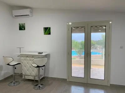 a white room with two stools and a counter and a pool at U FILANCIU in Olmeto