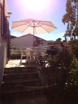 a patio with a table and an umbrella at Villa Oliera in Saint-Florent
