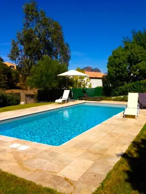 a swimming pool with two chairs and an umbrella at Villa Oliera in Saint-Florent