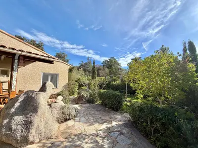 a garden with a large rock next to a house at Villa Argentella, Santa Giulia in Porto-Vecchio