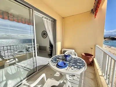 a table and chairs on a balcony with a view of the ocean at Studio Corse Azur pieds dans l'eau Ajaccio in Ajaccio