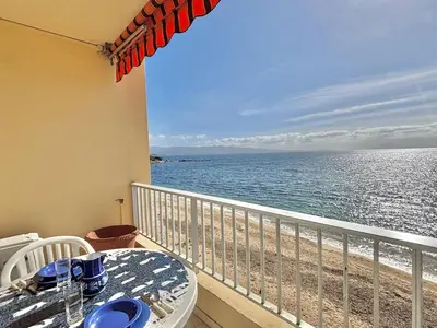 a balcony with a table and a view of the ocean at Studio Corse Azur pieds dans l'eau Ajaccio in Ajaccio