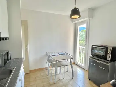 a kitchen with a table and a small table with chairs at Studio l'orée du bois AJACCIO in Ajaccio