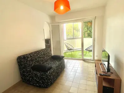 a living room with a black couch and a window at Studio l'orée du bois AJACCIO in Ajaccio
