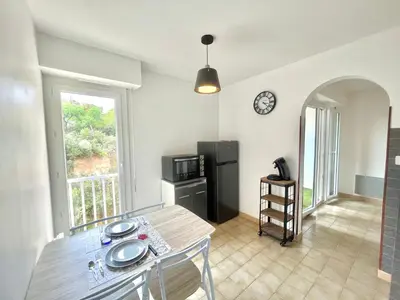 a kitchen with a dining table and a refrigerator at Studio l'orée du bois AJACCIO in Ajaccio