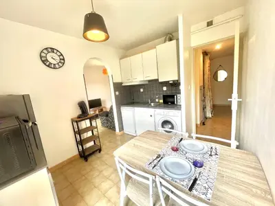 a kitchen and dining room with a table and a clock at Studio l'orée du bois AJACCIO in Ajaccio