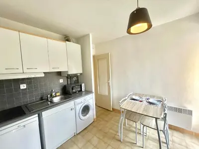 a kitchen with a sink and a table with a washing machine at Studio l'orée du bois AJACCIO in Ajaccio