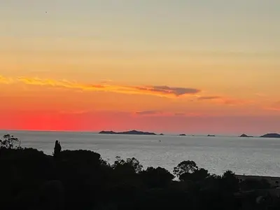 a sunset over the ocean with a person standing on a hill at L'Orangeraie de Portigliolo - Vue mer 4 chambres in Coti-Chiavari