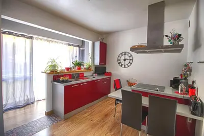 a kitchen with red cabinets and a table with chairs at Appartement Le Kent centre ville AJACCIO in Ajaccio