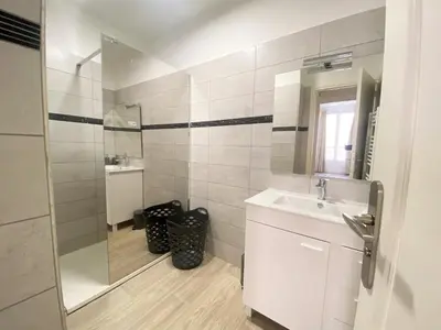 a white bathroom with a sink and a mirror at Appartement Sacré Coeur 6 couchages AJACCIO in Ajaccio