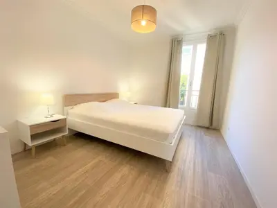 a white bedroom with a large bed and a window at Appartement Sacré Coeur 6 couchages AJACCIO in Ajaccio