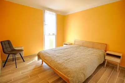 a bedroom with yellow walls and a bed and a chair at Appartement Eugénie centre-ville Ajaccio in Ajaccio