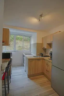 a kitchen with wooden cabinets and a white refrigerator at Appartement Eugénie centre-ville Ajaccio in Ajaccio