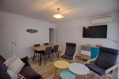 a living room with a table and chairs and a tv at Appartement Eugénie centre-ville Ajaccio in Ajaccio