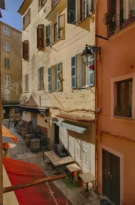 an alley in an old building with tables and an umbrella at Studio Conventionnel Chiappe Vieille ville Ajaccio in Ajaccio