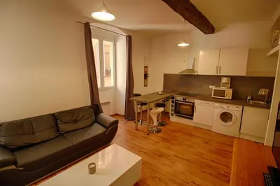 a living room with a couch and a kitchen at Studio Conventionnel Chiappe Vieille ville Ajaccio in Ajaccio